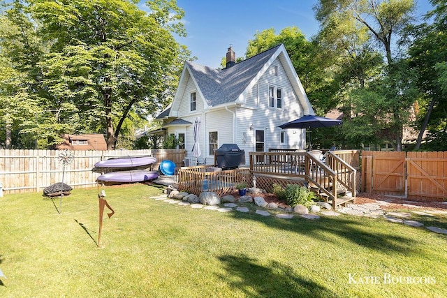 140 S Monroe St NE, Rockford, MI 49341 - rear view of house featuring a wooden deck, a fenced backyard, a gate, a chimney, and roof with shingles
