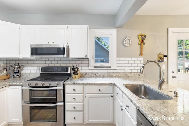140 S Monroe St NE, Rockford, MI 49341 - kitchen featuring appliances with stainless steel finishes, light stone countertops, and white cabinets