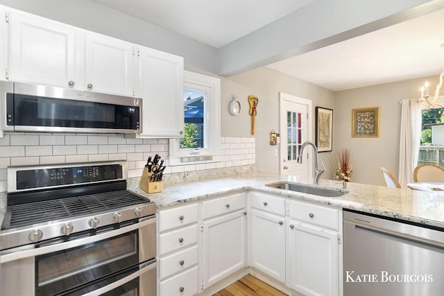 140 S Monroe St NE, Rockford, MI 49341 - kitchen with appliances with stainless steel finishes, tasteful backsplash, light stone counters, and white cabinetry