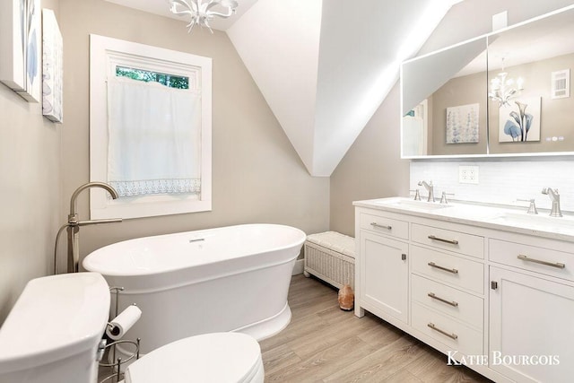 140 S Monroe St NE, Rockford, MI 49341 - full bathroom with wood finished floors, a soaking tub, double vanity, backsplash, and lofted ceiling
