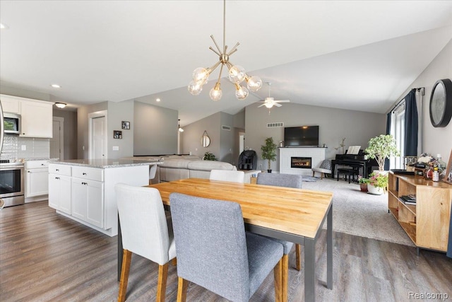 5606 Chatham Ln, Grand Blanc, MI 48439 - dining room featuring dark wood-style flooring, a ceiling fan, a glass covered fireplace, lofted ceiling, and a chandelier