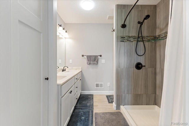 5606 Chatham Ln, Grand Blanc, MI 48439 - bathroom with double vanity, a tile shower, and wood finished floors