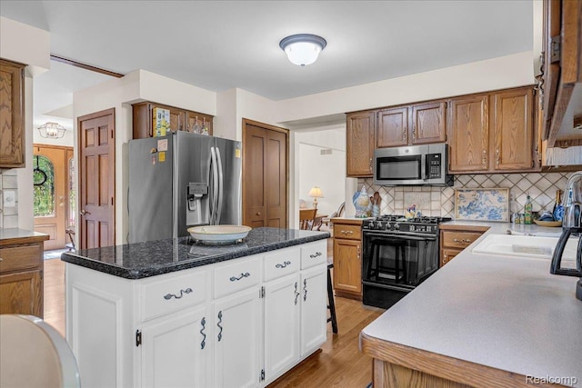 24842 White Plains Dr, Novi, MI 48374 - kitchen with stainless steel appliances, light wood-style floors, tasteful backsplash, white cabinets, and a kitchen island