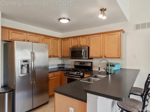 35033 Windsor Dr, New Baltimore, MI 48047 - kitchen featuring appliances with stainless steel finishes, a peninsula, dark countertops, a breakfast bar, and light tile patterned floors