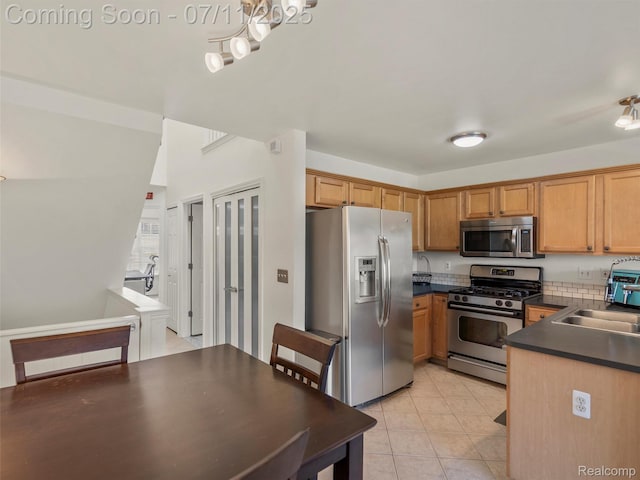 35033 Windsor Dr, New Baltimore, MI 48047 - kitchen with stainless steel appliances, dark countertops, light tile patterned floors, a chandelier, and brown cabinets