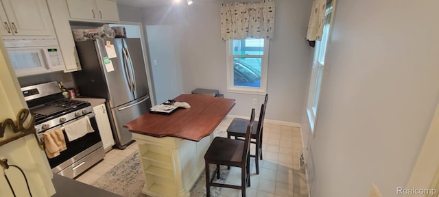 1644 Marylestone Dr, West Bloomfield, MI 48324 - kitchen featuring appliances with stainless steel finishes, white cabinetry, a breakfast bar area, dark countertops, and light tile patterned floors