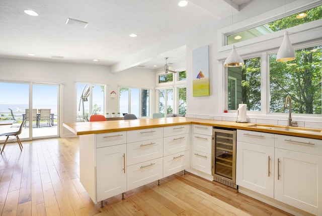 6881 Helena St, West Olive, MI 49460 - kitchen with wine cooler, butcher block counters, recessed lighting, light wood-style floors, and white cabinetry