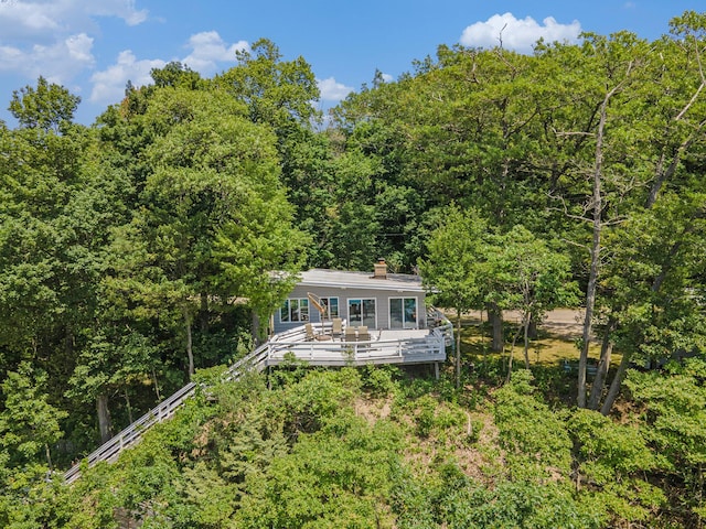 6881 Helena St, West Olive, MI 49460 - back of property with a view of trees, a deck, and a chimney
