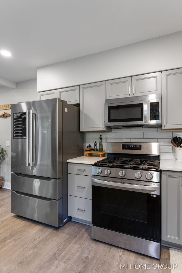 3255 Prairie St SW, Grandville, MI 49418 - kitchen with stainless steel appliances, gray cabinetry, decorative backsplash, and light countertops