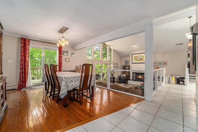 4729 Curtis Ln, Clarkston, MI 48346 - dining room featuring a baseboard radiator, light wood-style flooring, a fireplace, a chandelier, and lofted ceiling