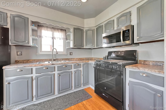 34060 Avondale St, Westland, MI 48186 - kitchen featuring black gas stove, stainless steel microwave, gray cabinetry, and light wood-type flooring