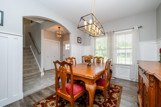 4785 Lauren Ln, Saint Joseph, MI 49085 - dining area featuring a decorative wall, arched walkways, a chandelier, wainscoting, and stairway