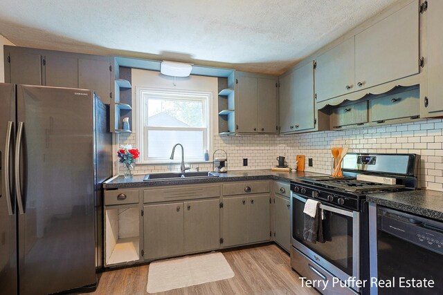 2025 Whitehall Rd, Muskegon, MI 49445 - kitchen with stainless steel appliances, dark countertops, light wood-style flooring, tasteful backsplash, and a textured ceiling