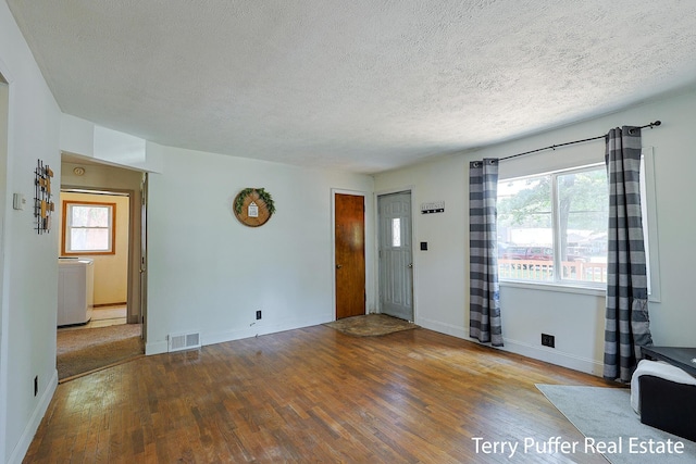 2025 Whitehall Rd, Muskegon, MI 49445 - unfurnished living room with wood finished floors, a textured ceiling, and washer / dryer