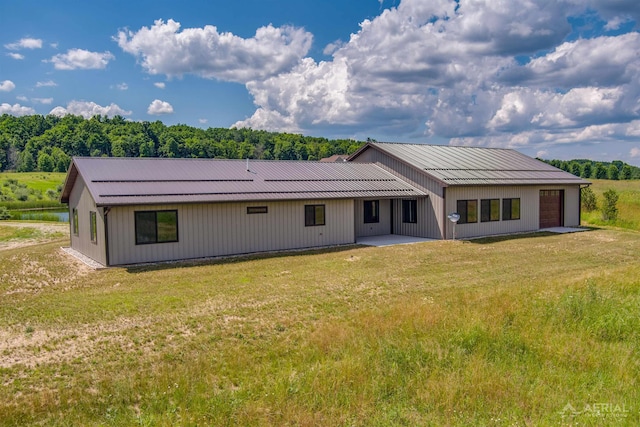 4646 Lehman Rd, West Branch, MI 48661 - rear view of house featuring a yard, an attached garage, a patio, and a metal roof