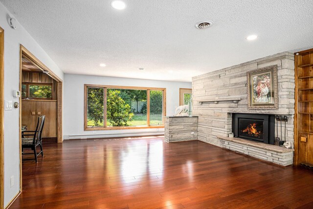 929 N Park Rd, Benton Harbor, MI 49022 - unfurnished living room featuring a textured ceiling, a fireplace, wood-type flooring, recessed lighting, and a baseboard heating unit