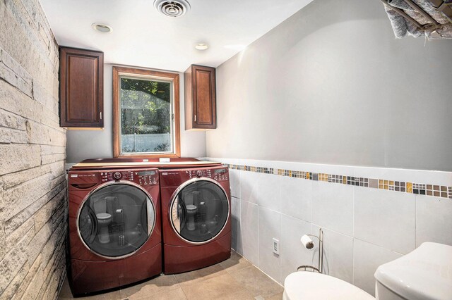 929 N Park Rd, Benton Harbor, MI 49022 - washroom with washing machine and dryer, cabinet space, tile walls, light tile patterned flooring, and a wainscoted wall