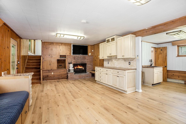 929 N Park Rd, Benton Harbor, MI 49022 - kitchen with open floor plan, wood walls, light wood-style flooring, and a brick fireplace