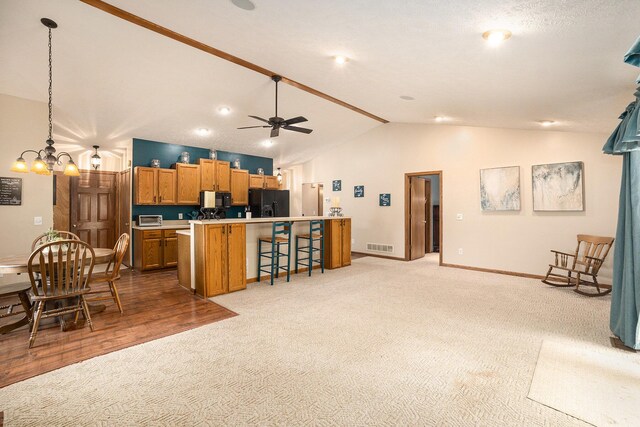 1972 Red Pine Dr, Dorr, MI 49323 - kitchen featuring black appliances, light carpet, lofted ceiling, brown cabinets, and a breakfast bar