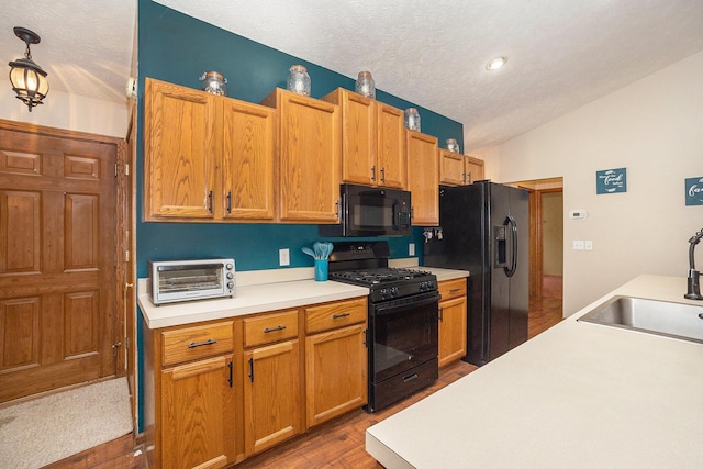1972 Red Pine Dr, Dorr, MI 49323 - kitchen with black appliances, light countertops, wood finished floors, vaulted ceiling, and a textured ceiling
