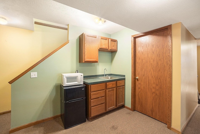 1972 Red Pine Dr, Dorr, MI 49323 - kitchen with white microwave, light colored carpet, dark countertops, and fridge
