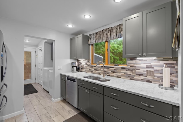3129 Oakshade Dr, Manitou Beach, MI 49253 - kitchen with stainless steel dishwasher, washing machine and dryer, backsplash, light stone counters, and gray cabinetry