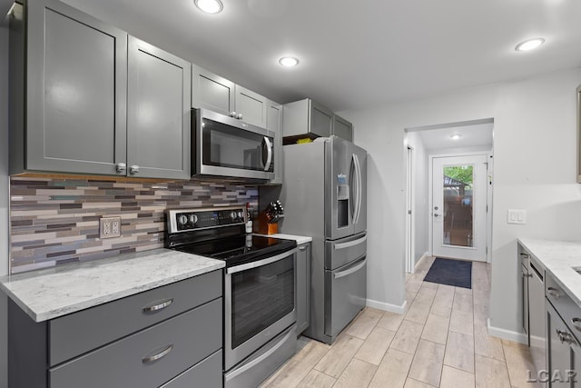 3129 Oakshade Dr, Manitou Beach, MI 49253 - kitchen featuring stainless steel appliances, gray cabinetry, decorative backsplash, light stone countertops, and wood tiled floors