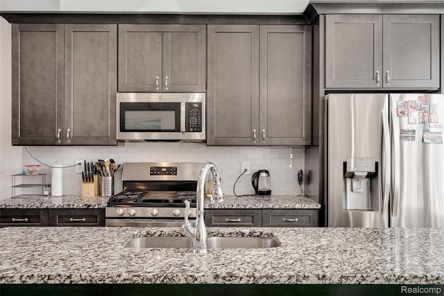 5973 Stella, Troy, MI 48085 - kitchen featuring appliances with stainless steel finishes, light stone countertops, backsplash, and dark brown cabinetry