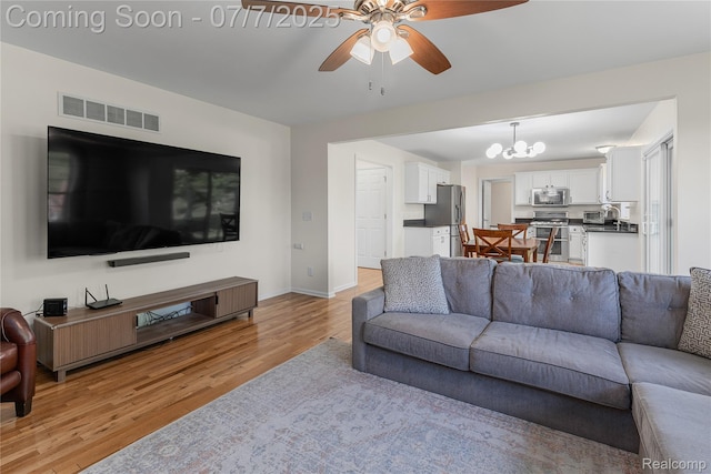 48840 Greenwich Cir, Canton, MI 48188 - living room with light wood-style floors, ceiling fan, and a chandelier