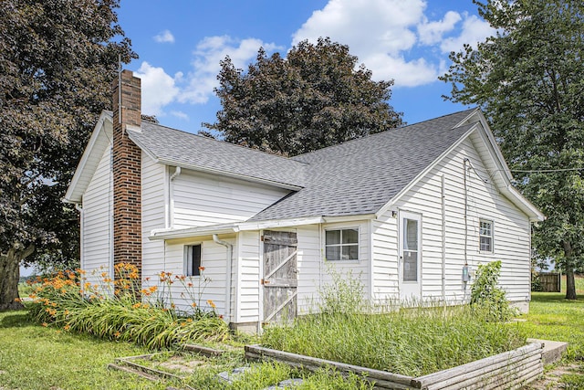 238 Maple Rd, Quincy, MI 49082 - view of side of home featuring a chimney, roof with shingles, a vegetable garden, and a yard