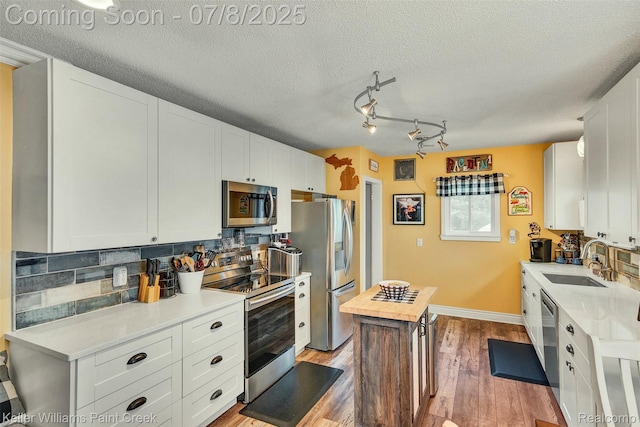 1726 Oxford Rd, Berkley, MI 48072 - kitchen with appliances with stainless steel finishes, backsplash, light wood-style flooring, white cabinets, and a textured ceiling