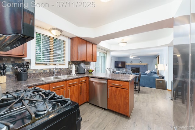 8527 Congress Dr, Canton, MI 48187 - kitchen featuring stainless steel appliances, a raised ceiling, dark countertops, light wood-style floors, and a peninsula