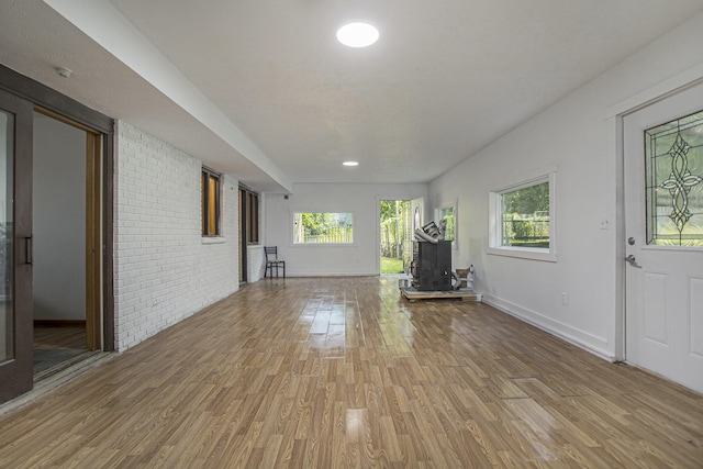 14083 M37, Battle Creek, MI 49017 - unfurnished living room featuring light wood finished floors, a wood stove, and brick wall