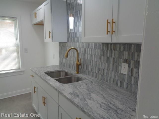 18259 Pinehurst St, Detroit, MI 48221 - kitchen with tasteful backsplash, white cabinetry, and light stone countertops