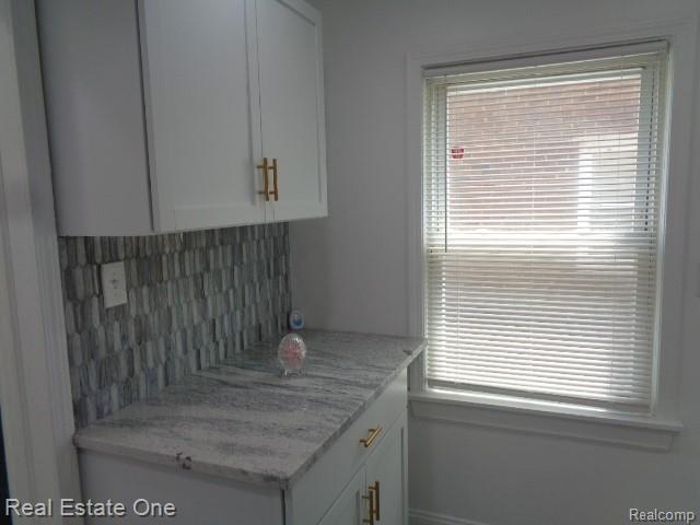 18259 Pinehurst St, Detroit, MI 48221 - kitchen featuring tasteful backsplash, white cabinetry, healthy amount of natural light, and light stone countertops