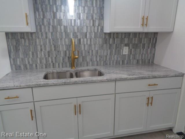 18259 Pinehurst St, Detroit, MI 48221 - kitchen featuring white cabinetry, decorative backsplash, and light stone countertops