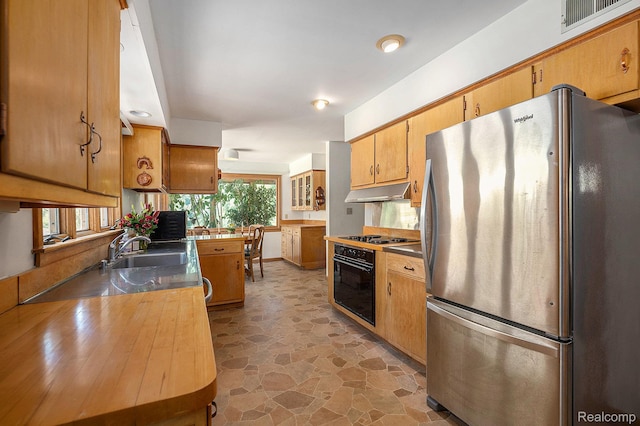6400 N Rochester Rd, Rochester Hills, MI 48306 - kitchen with freestanding refrigerator, black oven, under cabinet range hood, cooktop, and light stone finish floors