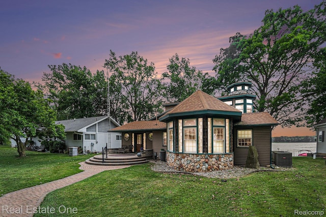 634 Dorbert Dr, Munith, MI 49259 - rear view of house featuring a yard, a shingled roof, and stone siding
