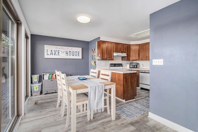 3265 Elmwood Beach Rd, Middleville, MI 49333 - kitchen with dishwashing machine, light wood-type flooring, under cabinet range hood, light countertops, and brown cabinets