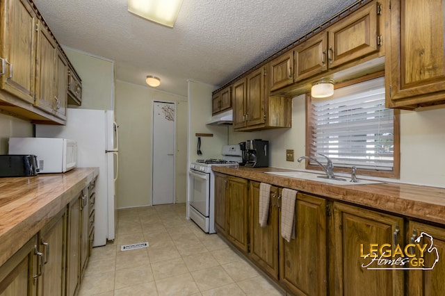 1163 Maple Leaf Ln NW, Walker, MI 49534 - kitchen with white appliances, wood counters, brown cabinets, under cabinet range hood, and light tile patterned floors
