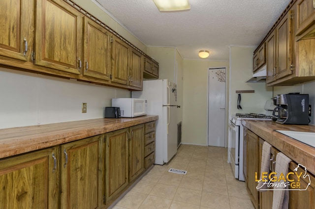 1163 Maple Leaf Ln NW, Walker, MI 49534 - kitchen with white appliances, under cabinet range hood, brown cabinets, wood counters, and a textured ceiling
