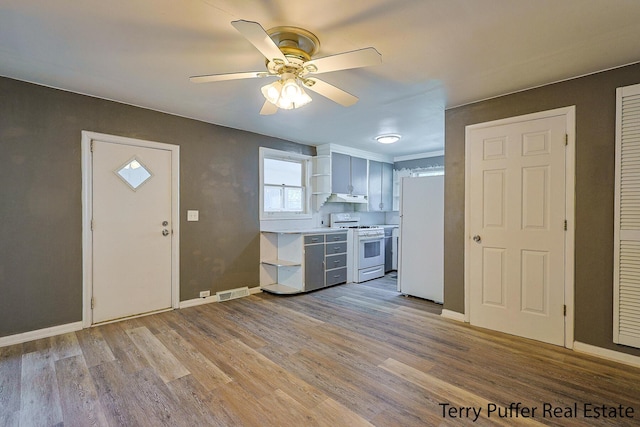 1966 Roilson St, Muskegon, MI 49441 - kitchen with white appliances, under cabinet range hood, light wood finished floors, a ceiling fan, and light countertops