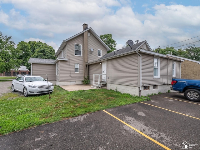 926 E Front St, Monroe, MI 48161 - view of property exterior featuring uncovered parking, a chimney, a lawn, and entry steps