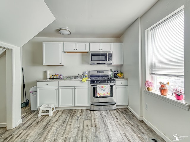 926 E Front St, Monroe, MI 48161 - kitchen with stainless steel appliances, light wood-style flooring, light countertops, and white cabinets
