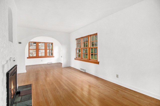 838 Lakeway Ave, Kalamazoo, MI 49001 - unfurnished living room featuring arched walkways, a glass covered fireplace, and wood finished floors