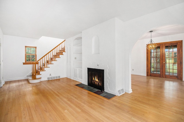 838 Lakeway Ave, Kalamazoo, MI 49001 - unfurnished living room featuring healthy amount of natural light, light wood-style flooring, built in features, and arched walkways