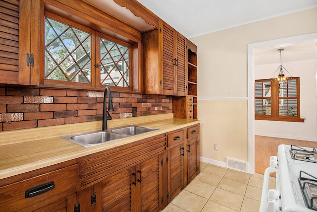 838 Lakeway Ave, Kalamazoo, MI 49001 - kitchen featuring white gas range oven, light countertops, wainscoting, brown cabinets, and a chandelier