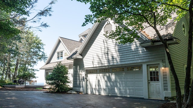4569 N Ridge Rd, Mears, MI 49436 - view of property exterior featuring asphalt driveway, a garage, and a shingled roof