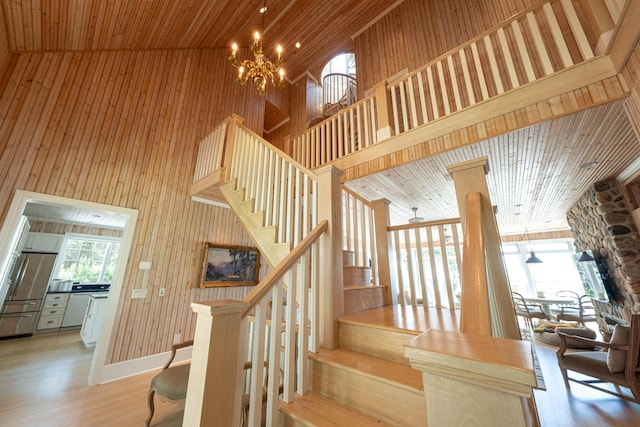 4569 N Ridge Rd, Mears, MI 49436 - stairway with a towering ceiling, a chandelier, wooden walls, wood finished floors, and wooden ceiling