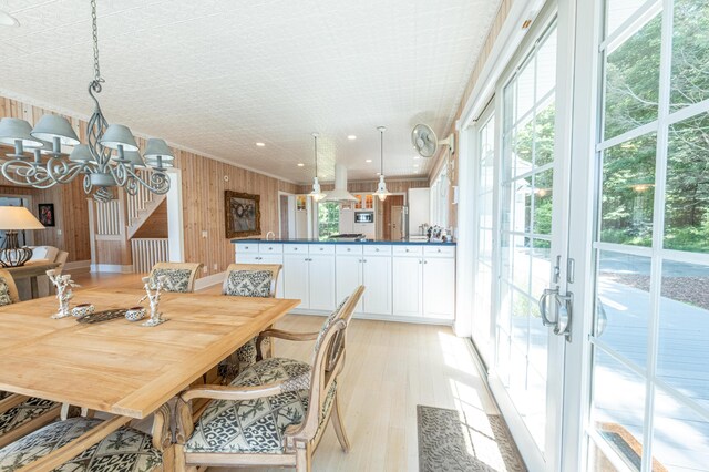 4569 N Ridge Rd, Mears, MI 49436 - dining area with a chandelier, light wood-type flooring, and wooden walls